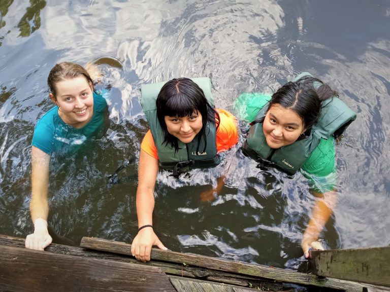 3 young women swimming in a pond