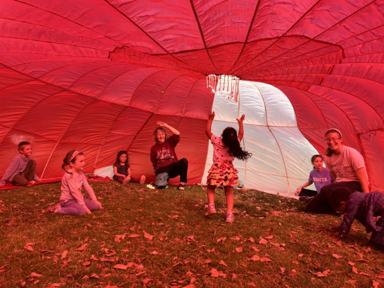 Children playing under a big parachute tarp